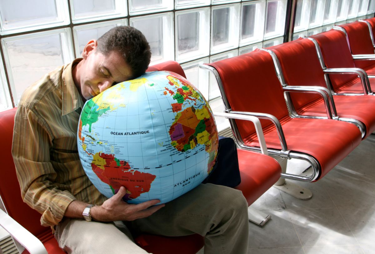 man falling asleep on a globe ball